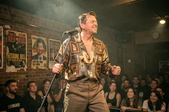 Chanteur américain rock années 70 sur scène dans un club avec chemise en soie vintage et pantalon pattes d'éléphant